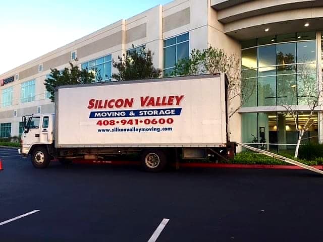 Silicon Valley Moving & Storage box truck loaded at the entrance of a Bay Area office building during an evening corporate relocation