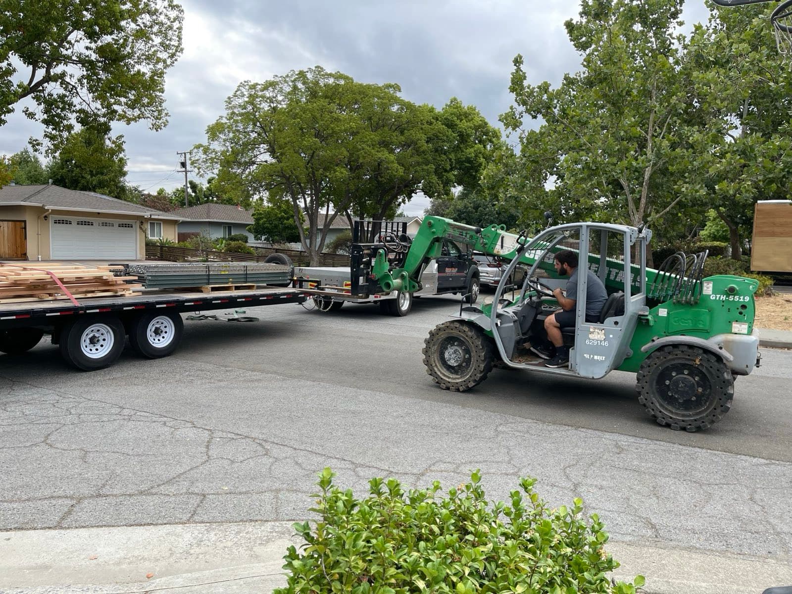 Silicon Valley Moving & Storage telehandler loading construction materials onto a flatbed trailer during a Bay Area site cleanout